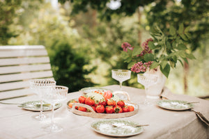 Somrig dukning utomhus med vackert porsling och jordgubbar på ett fat